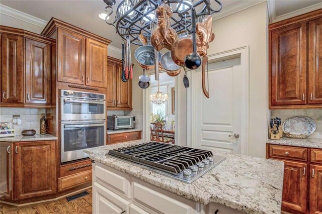 95 Weslyan Way, Oxford, GA 30054 - kitchen featuring a chandelier, appliances with stainless steel finishes, backsplash, light stone counters, and ornamental molding