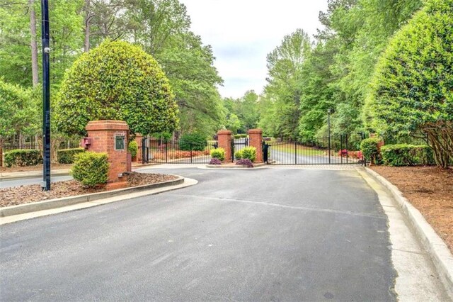 95 Weslyan Way, Oxford, GA 30054 - view of asphalt street featuring a gate, curbs, a gated entry, and street lighting