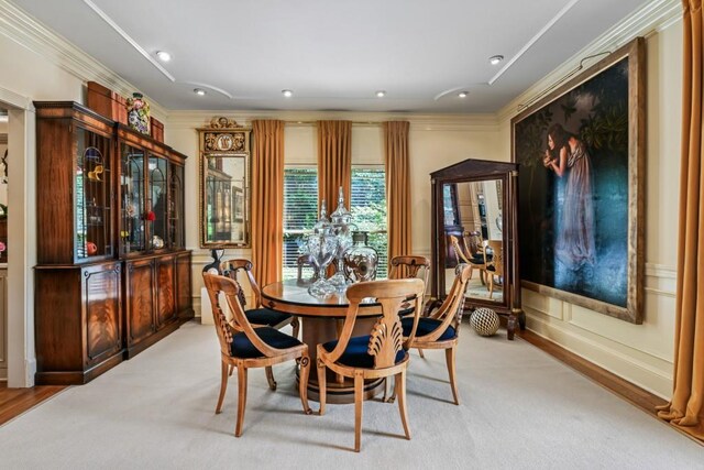 dining room with ornamental molding and light colored carpet
