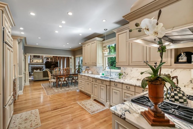 kitchen with crown molding, cream cabinets, a sink, light wood-style flooring, and backsplash
