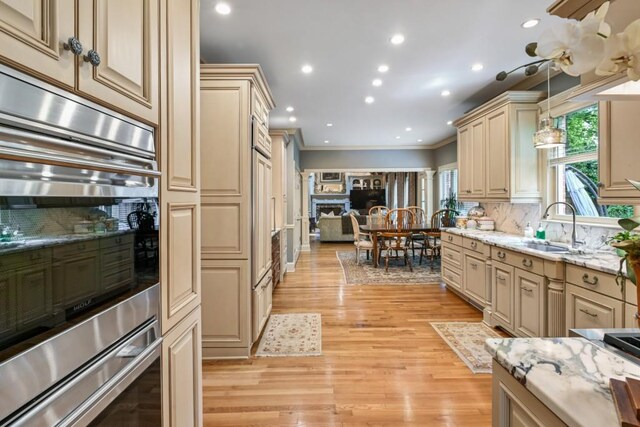 kitchen with crown molding, backsplash, a sink, and cream cabinetry