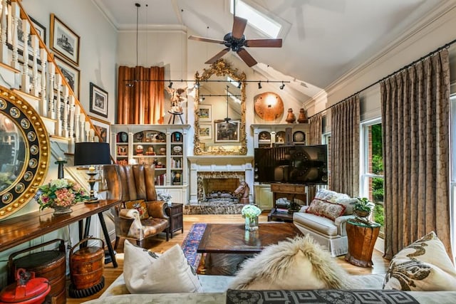 sitting room with ceiling fan, a premium fireplace, high vaulted ceiling, wood finished floors, and ornamental molding