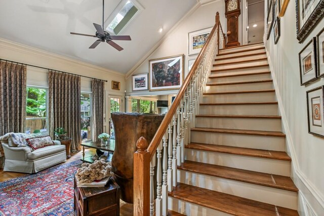 staircase featuring a ceiling fan, high vaulted ceiling, and ornamental molding