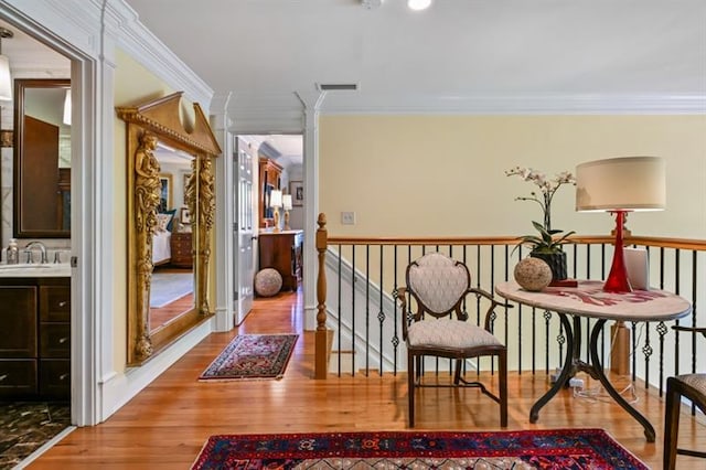 hall with a sink, ornamental molding, and wood finished floors