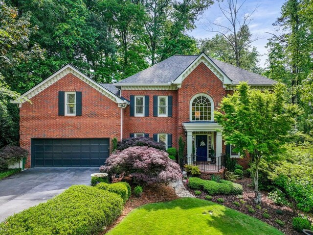 view of front of home featuring driveway, a garage, brick siding, a front lawn, and a shingled roof