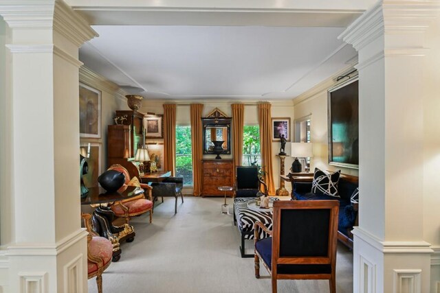 carpeted living area featuring crown molding and ornate columns
