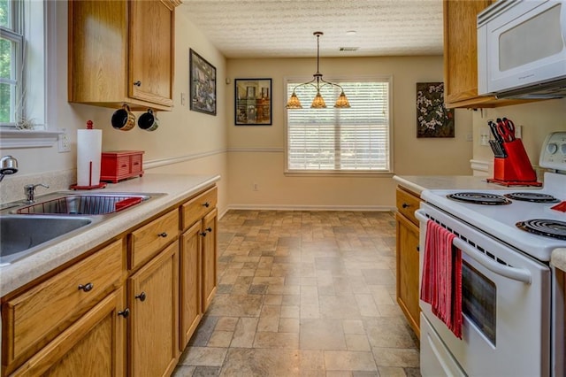 kitchen with a sink, pendant lighting, baseboards, white appliances, and light countertops