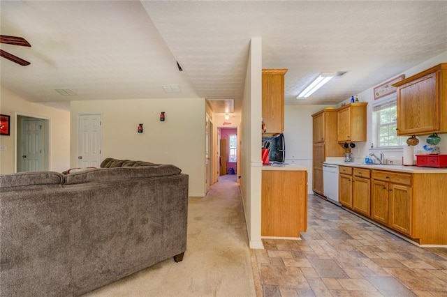 kitchen featuring a sink, ceiling fan, open floor plan, light countertops, and white dishwasher