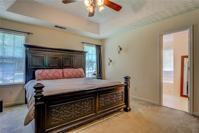 bedroom with baseboards, a raised ceiling, visible vents, and light colored carpet