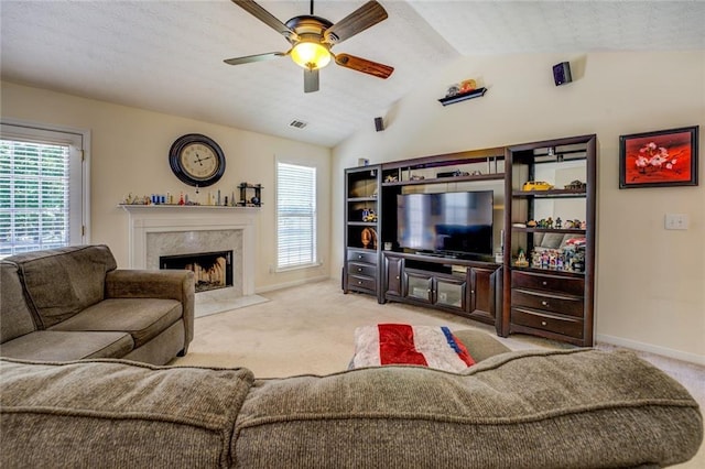 living area with lofted ceiling, light carpet, a fireplace, and ceiling fan