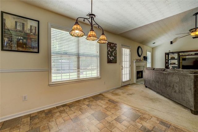 living room featuring baseboards, stone finish flooring, a fireplace, and a ceiling fan