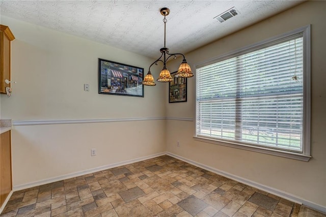 unfurnished dining area featuring stone finish flooring, a healthy amount of sunlight, baseboards, and visible vents