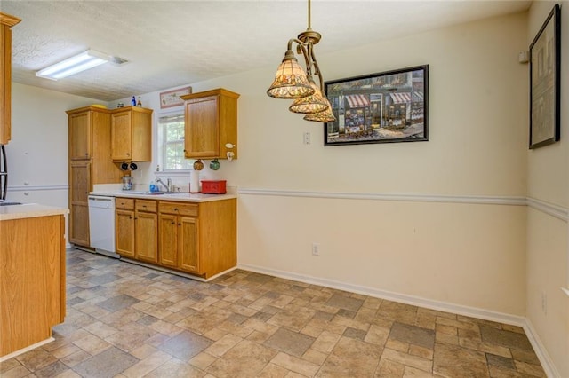 kitchen with dishwasher, light countertops, stone finish flooring, and a sink