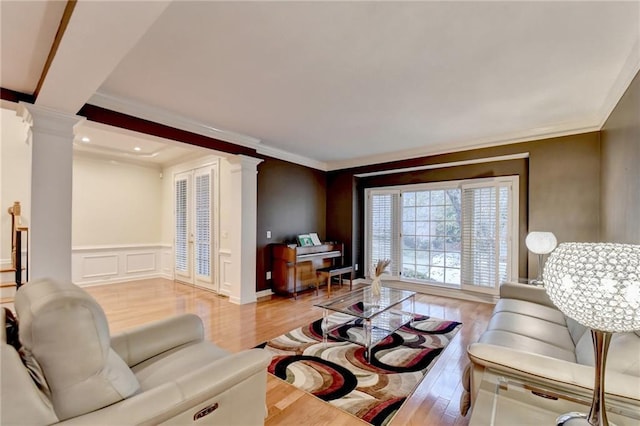 3565 Hickory Branch Trl, Suwanee, GA 30024 - living room featuring ornate columns, light wood finished floors, crown molding, a wainscoted wall, and a decorative wall