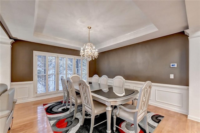 3565 Hickory Branch Trl, Suwanee, GA 30024 - dining space with a raised ceiling, a decorative wall, a chandelier, wood finished floors, and a wainscoted wall