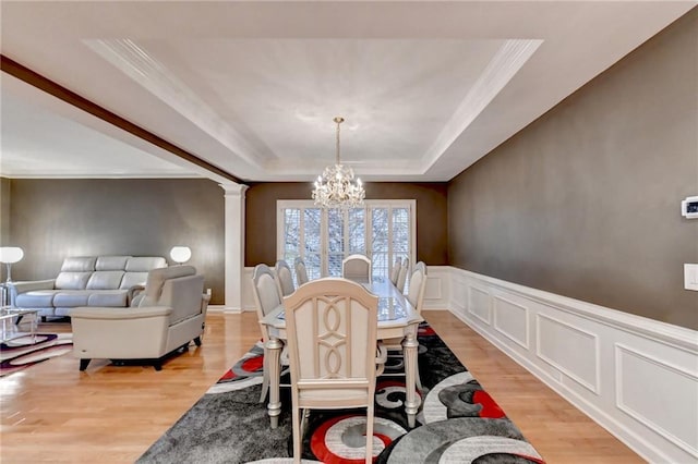 3565 Hickory Branch Trl, Suwanee, GA 30024 - dining room featuring a chandelier, a raised ceiling, light wood finished floors, decorative columns, and crown molding
