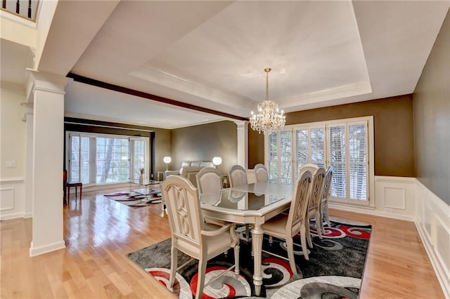3565 Hickory Branch Trl, Suwanee, GA 30024 - dining room featuring decorative columns, a decorative wall, a tray ceiling, a chandelier, and light wood-type flooring
