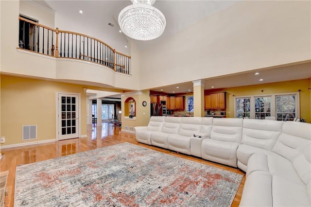 3565 Hickory Branch Trl, Suwanee, GA 30024 - living room with a chandelier, light wood finished floors, ornate columns, a towering ceiling, and baseboards