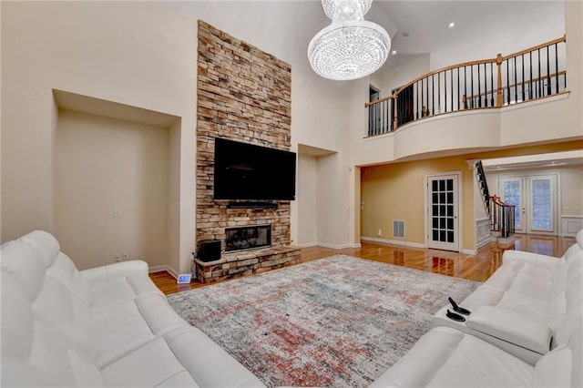 3565 Hickory Branch Trl, Suwanee, GA 30024 - living area featuring a high ceiling, a chandelier, wood finished floors, a stone fireplace, and baseboards