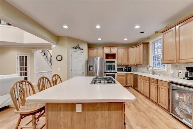 3565 Hickory Branch Trl, Suwanee, GA 30024 - kitchen featuring appliances with stainless steel finishes, wine cooler, a breakfast bar, light wood-type flooring, and tasteful backsplash