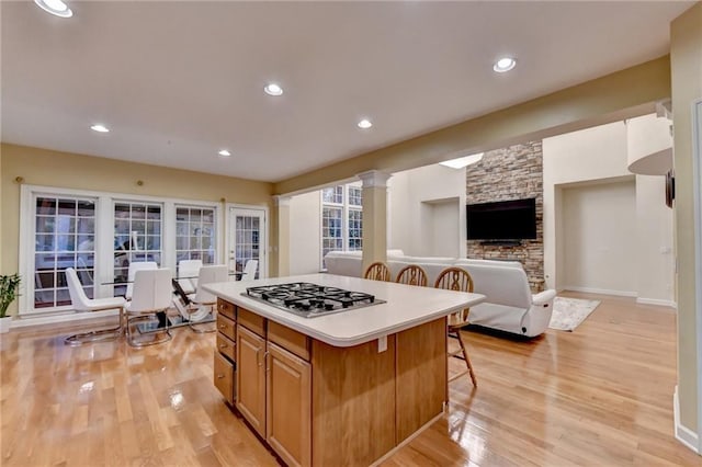 3565 Hickory Branch Trl, Suwanee, GA 30024 - kitchen featuring stainless steel gas stovetop, a breakfast bar, light wood-type flooring, a center island, and light countertops