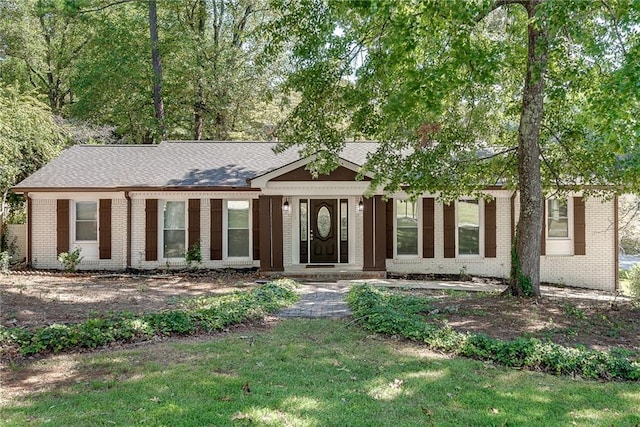 single story home with roof with shingles, a front lawn, and brick siding