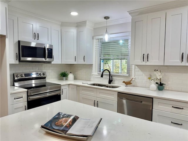 kitchen featuring crown molding, stainless steel appliances, backsplash, white cabinetry, and a sink