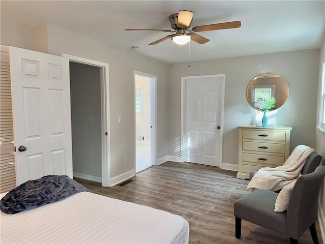 bedroom with a ceiling fan, visible vents, baseboards, and wood finished floors