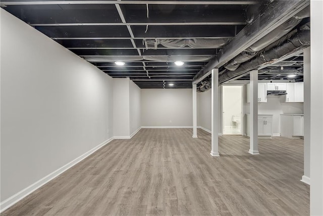 finished basement featuring light wood-style flooring and baseboards