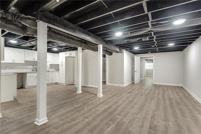 finished basement with light wood-type flooring and baseboards