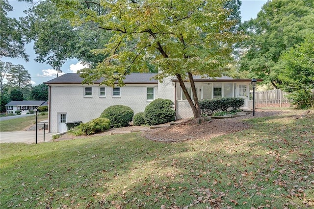 view of side of property with a yard, brick siding, and fence