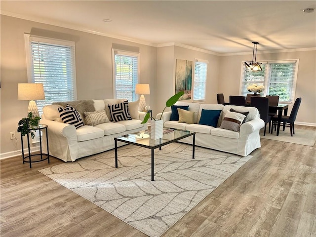 living room featuring an inviting chandelier, baseboards, ornamental molding, and wood finished floors