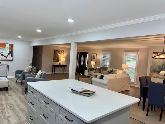 kitchen featuring crown molding, recessed lighting, light countertops, light wood-style flooring, and open floor plan