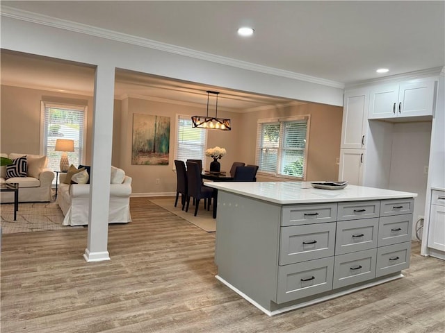 kitchen featuring hanging light fixtures, light wood-style flooring, light countertops, and crown molding