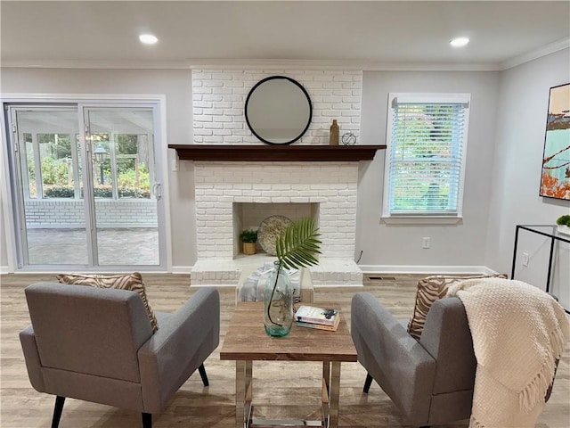 living area featuring crown molding, recessed lighting, a brick fireplace, wood finished floors, and baseboards