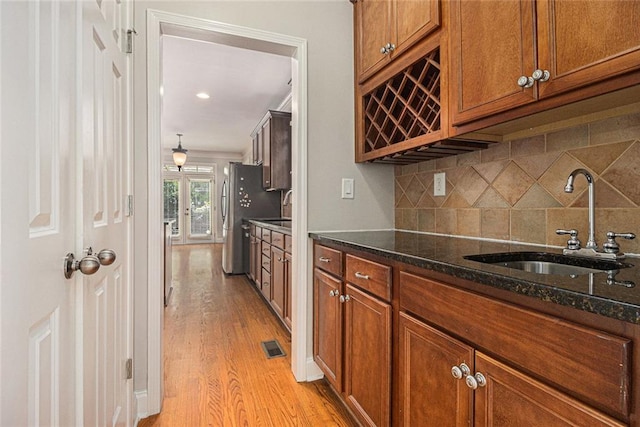 5575 Julian Pl, Atlanta, GA 30342 - kitchen with light wood-type flooring, brown cabinetry, backsplash, dark stone countertops, and freestanding refrigerator