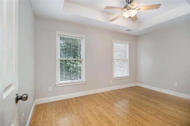 5575 Julian Pl, Atlanta, GA 30342 - empty room with a tray ceiling, healthy amount of natural light, light wood-style flooring, and ceiling fan