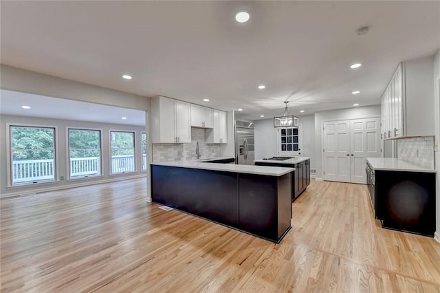 kitchen featuring light wood-style floors, light countertops, decorative backsplash, and built in refrigerator