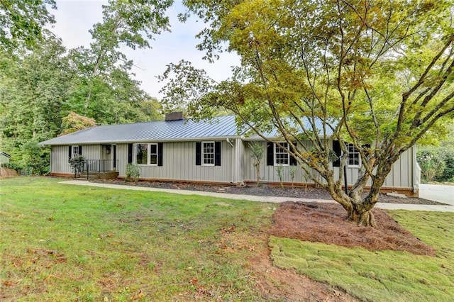 ranch-style home with a chimney, metal roof, a standing seam roof, a front lawn, and board and batten siding