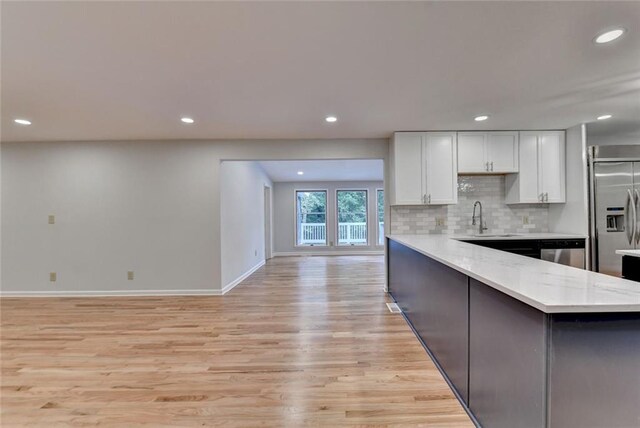 kitchen featuring light wood-style flooring, a sink, white cabinetry, appliances with stainless steel finishes, and backsplash