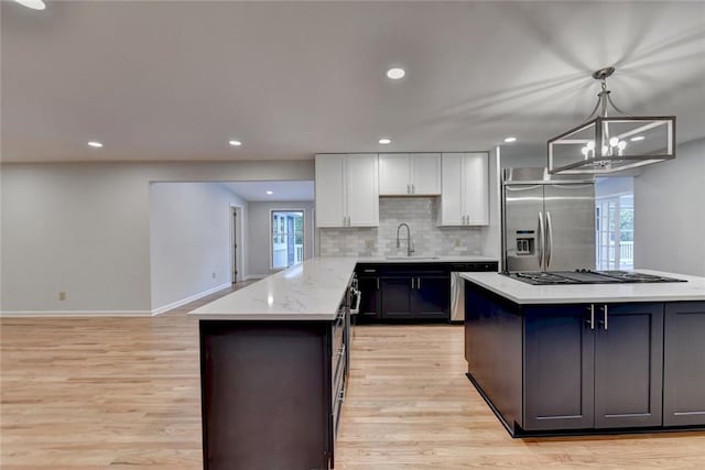 kitchen featuring a sink, white cabinetry, light wood-style floors, tasteful backsplash, and stainless steel built in refrigerator