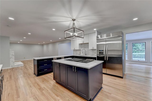 kitchen with light countertops, built in refrigerator, light wood-type flooring, and black electric cooktop