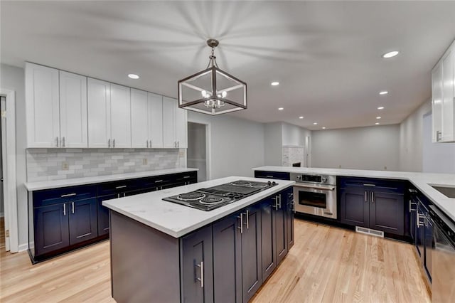 kitchen featuring light wood finished floors, white cabinetry, stovetop with downdraft, and oven