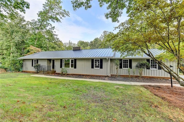 ranch-style home with a chimney, board and batten siding, a standing seam roof, metal roof, and a front lawn