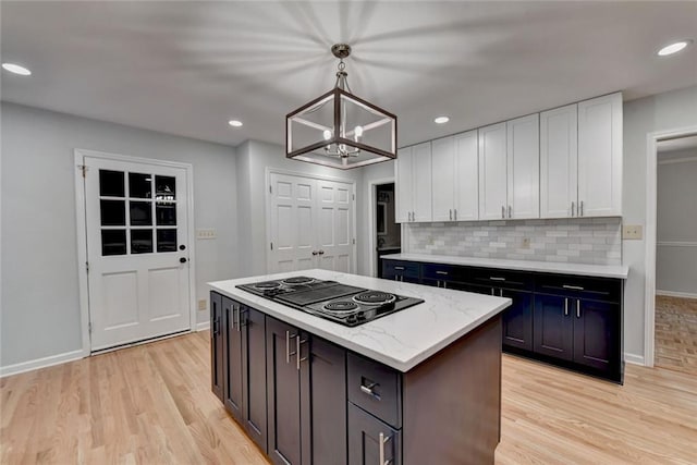 kitchen with light wood-style floors, white cabinets, backsplash, and black electric cooktop