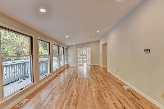 unfurnished living room featuring lofted ceiling, light wood finished floors, baseboards, and visible vents