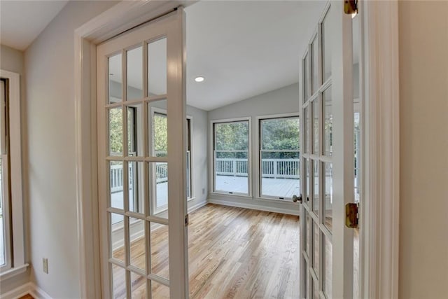 doorway to outside with french doors, vaulted ceiling, baseboards, and wood finished floors