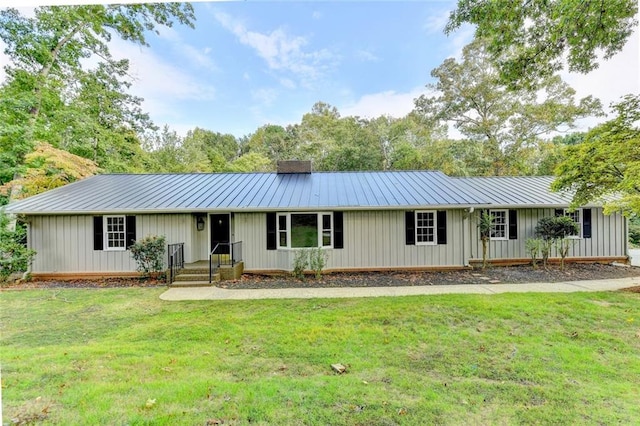 ranch-style house with a chimney, metal roof, a standing seam roof, and a front yard