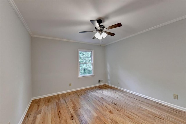 spare room with ceiling fan, visible vents, baseboards, light wood-type flooring, and crown molding