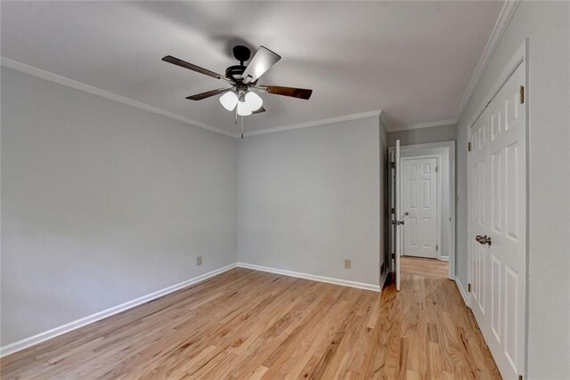 unfurnished bedroom featuring baseboards, ceiling fan, ornamental molding, light wood-style floors, and a closet